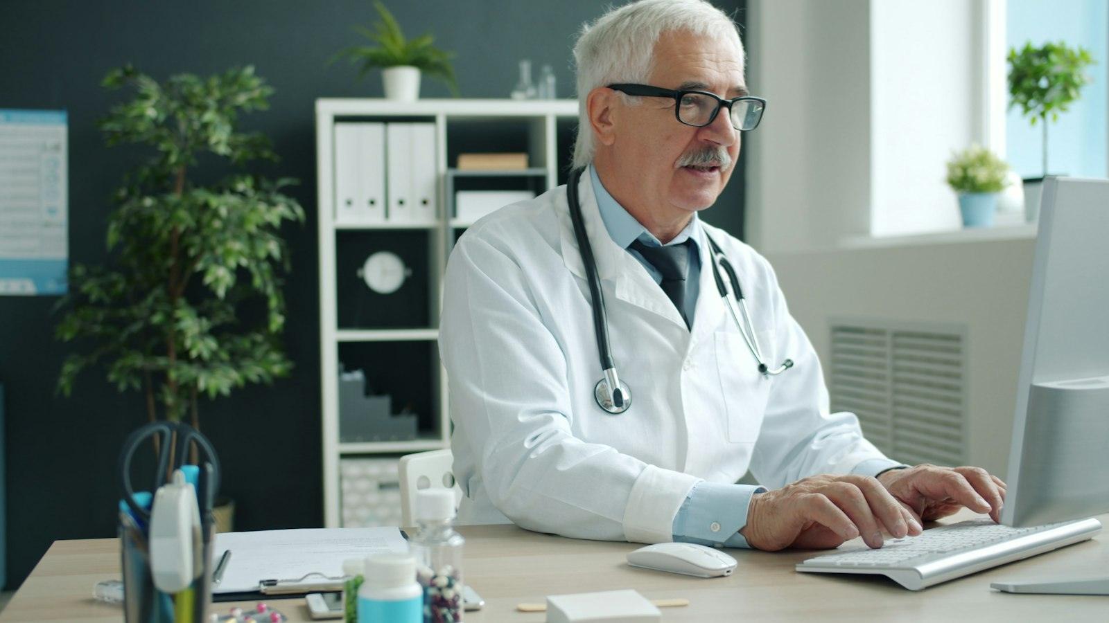 A physician working at a computer in a clinic office