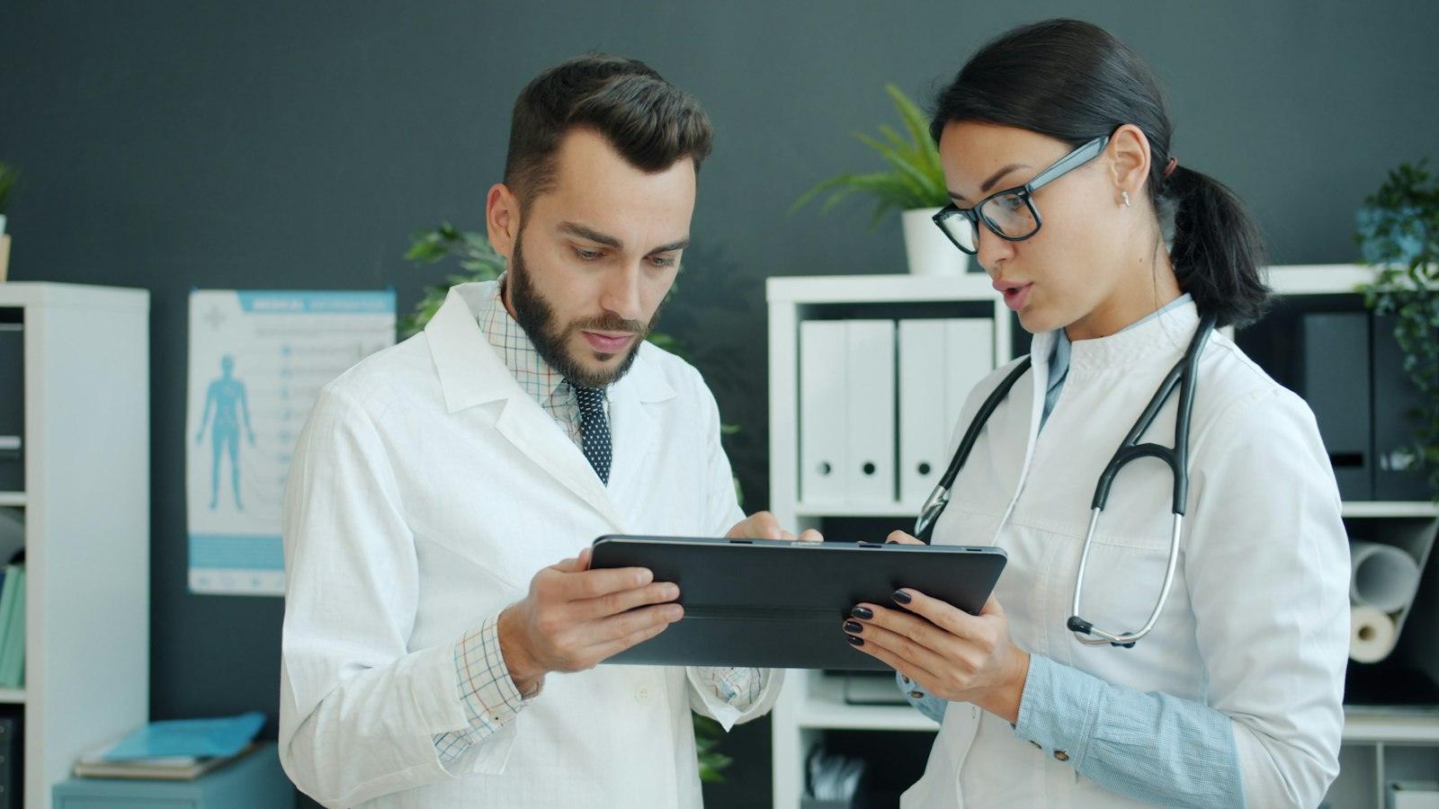 Two physicians reviewing patient information on a tablet