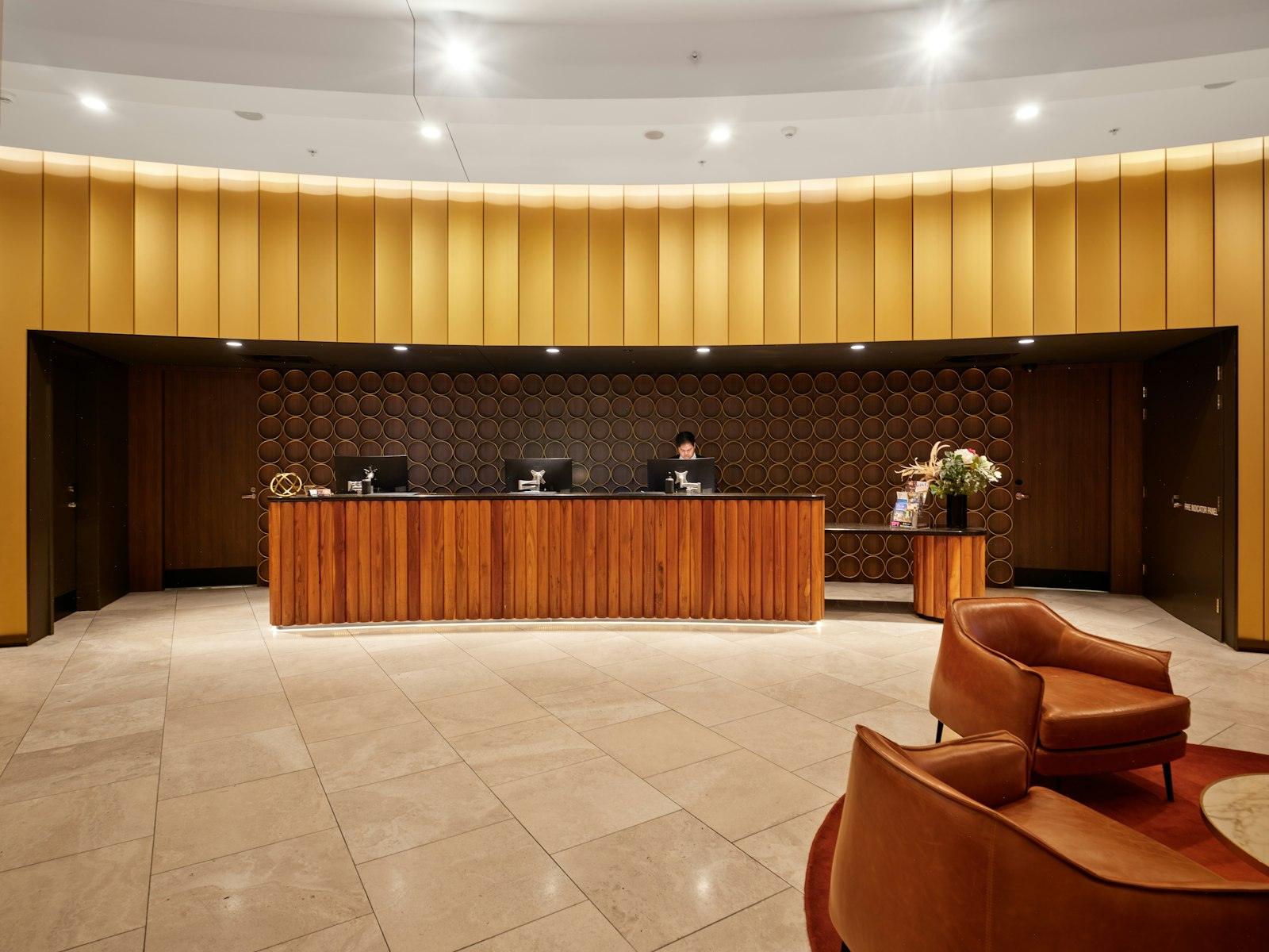 A hotel reception desk with wood paneling and lounge seating